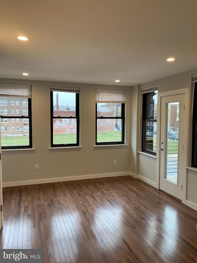 empty room with baseboards, dark wood-type flooring, and recessed lighting