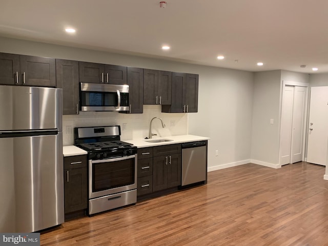 kitchen featuring light countertops, appliances with stainless steel finishes, a sink, and light wood-style floors