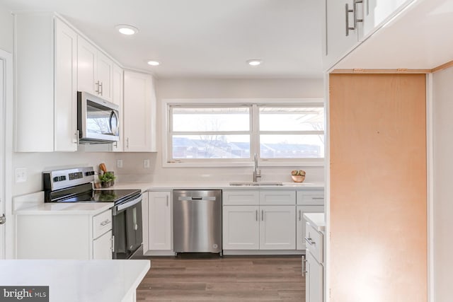 kitchen featuring white cabinetry, sink, stainless steel appliances, and hardwood / wood-style floors