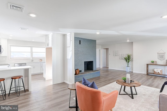 living room featuring a fireplace, light hardwood / wood-style floors, and sink