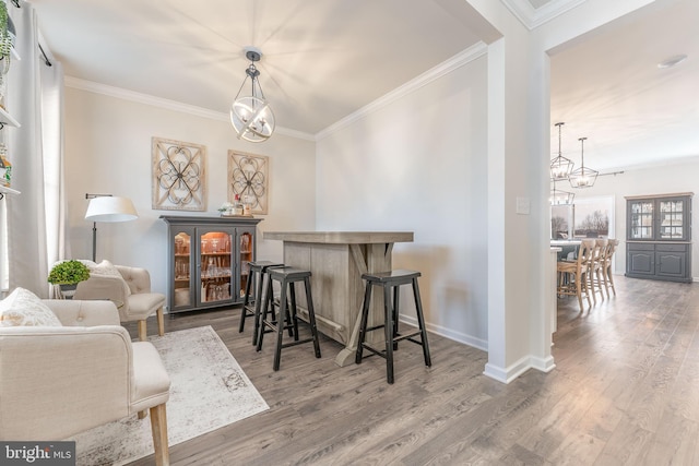 dining area with a chandelier, wood finished floors, and ornamental molding