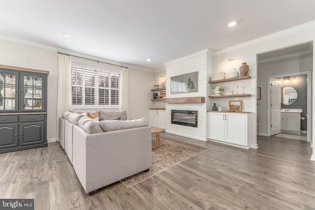 living room with recessed lighting, a fireplace, wood finished floors, baseboards, and crown molding