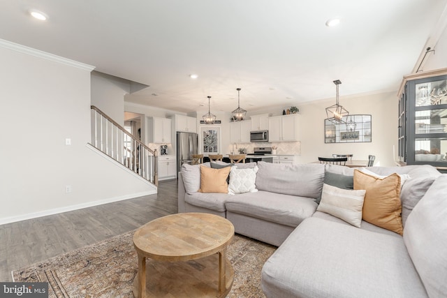 living room featuring baseboards, stairway, ornamental molding, wood finished floors, and recessed lighting