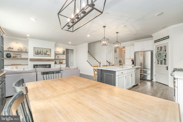 dining space featuring a large fireplace, stairway, ornamental molding, dark wood-type flooring, and recessed lighting