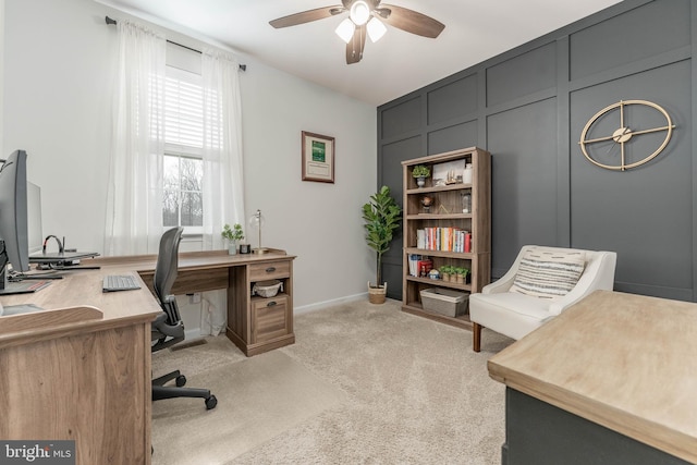 home office featuring light colored carpet, ceiling fan, and a decorative wall