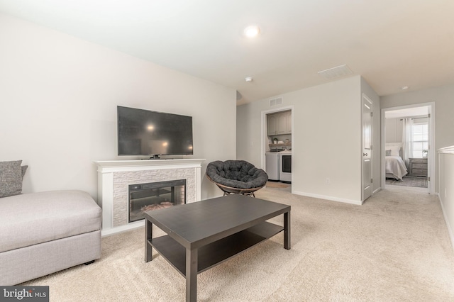 living room featuring baseboards, visible vents, a glass covered fireplace, and light colored carpet