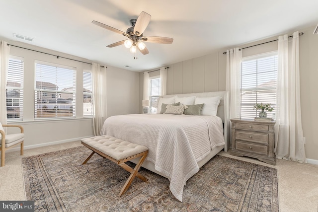 carpeted bedroom with baseboards, multiple windows, visible vents, and a ceiling fan