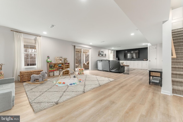 living area featuring baseboards, visible vents, stairs, light wood-style floors, and recessed lighting