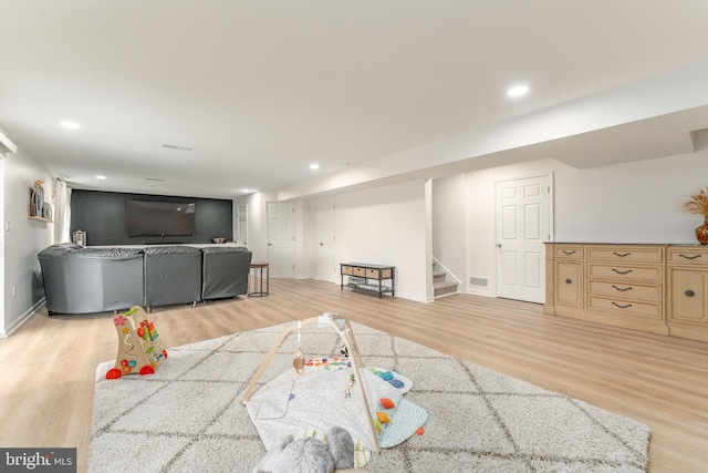 living room featuring light wood-style floors, recessed lighting, visible vents, and stairway