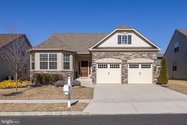 view of front of property featuring a shingled roof, an attached garage, a standing seam roof, stone siding, and driveway