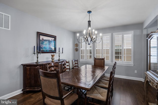 dining area featuring dark wood-type flooring, an inviting chandelier, visible vents, and baseboards