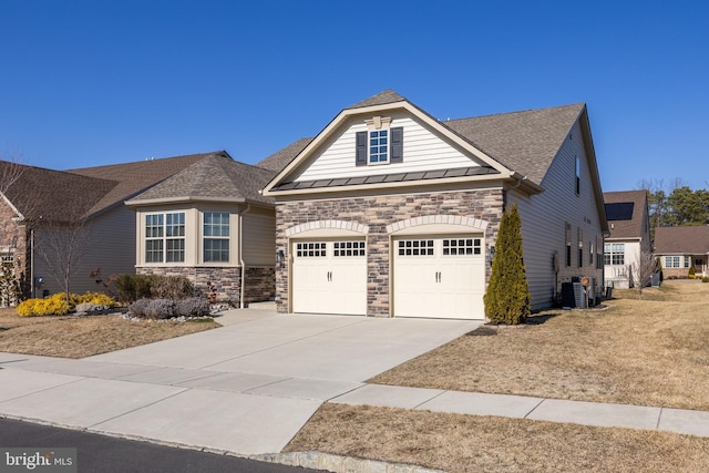 view of front of house featuring driveway, a garage, metal roof, a standing seam roof, and central AC