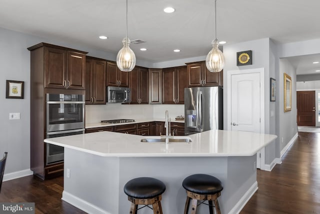 kitchen featuring visible vents, appliances with stainless steel finishes, dark wood-type flooring, light countertops, and a sink