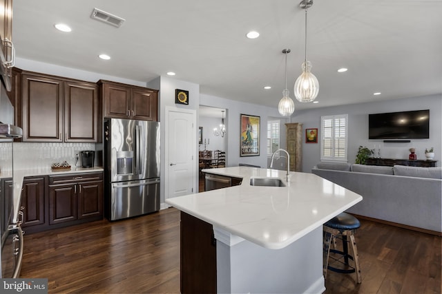 kitchen featuring visible vents, an island with sink, appliances with stainless steel finishes, dark wood-style flooring, and a sink