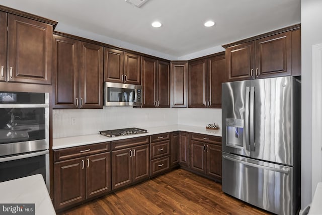 kitchen with dark brown cabinetry, recessed lighting, stainless steel appliances, light countertops, and dark wood finished floors