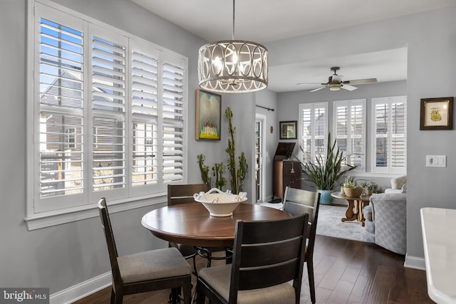 dining room featuring baseboards, dark wood-style flooring, and ceiling fan with notable chandelier