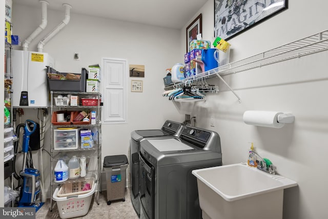 laundry area with laundry area, water heater, separate washer and dryer, and a sink