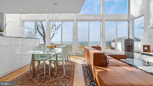 dining space with floor to ceiling windows, plenty of natural light, light wood-style floors, and a water view