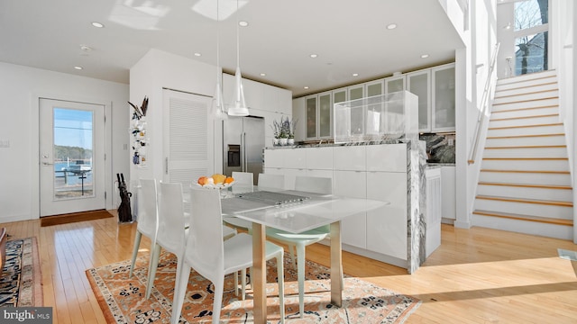 dining room with recessed lighting, light wood-type flooring, baseboards, and stairs