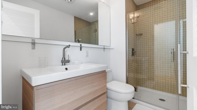 full bathroom featuring toilet, a stall shower, and vanity