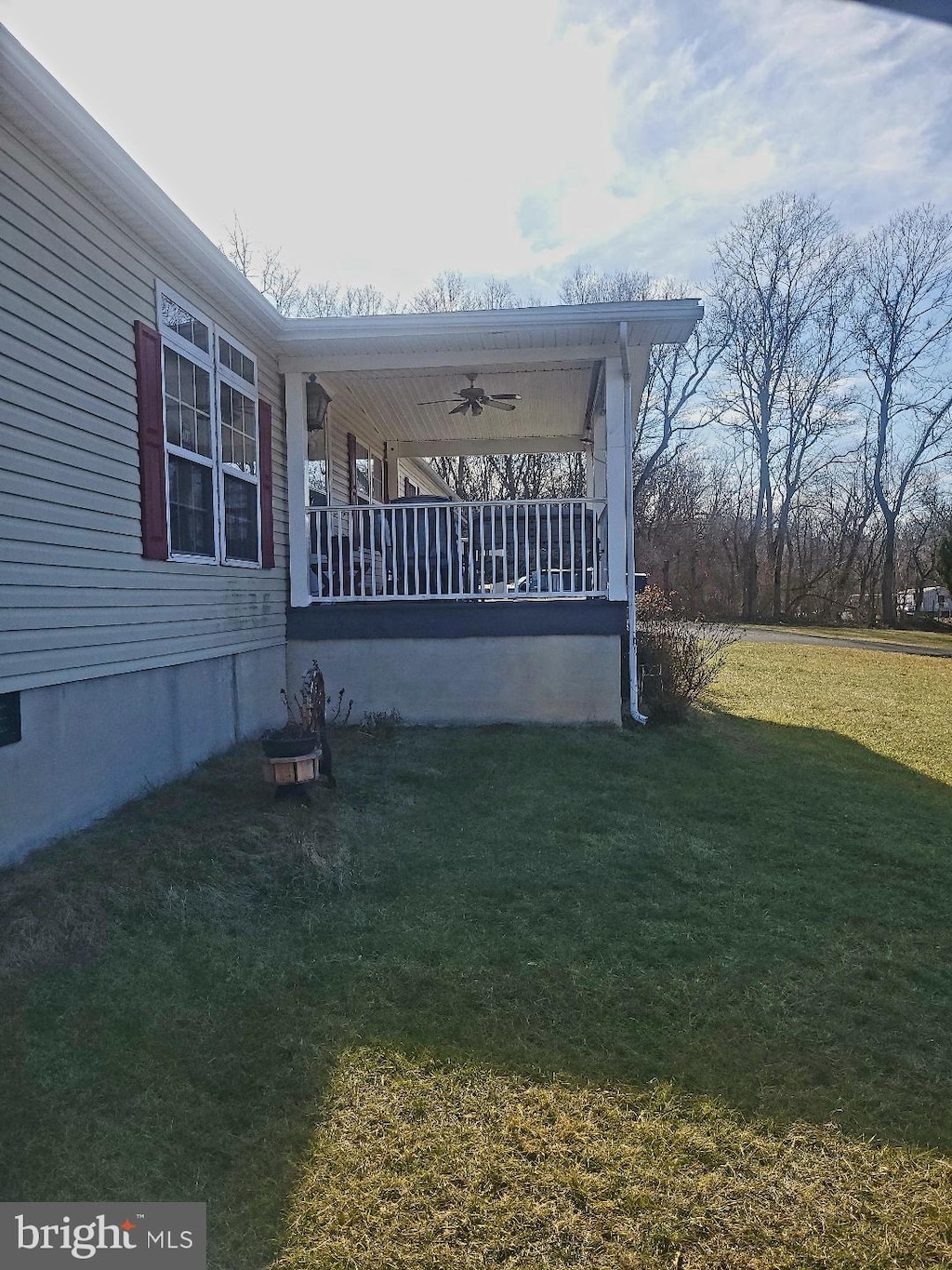 view of side of home with a lawn, ceiling fan, and a porch