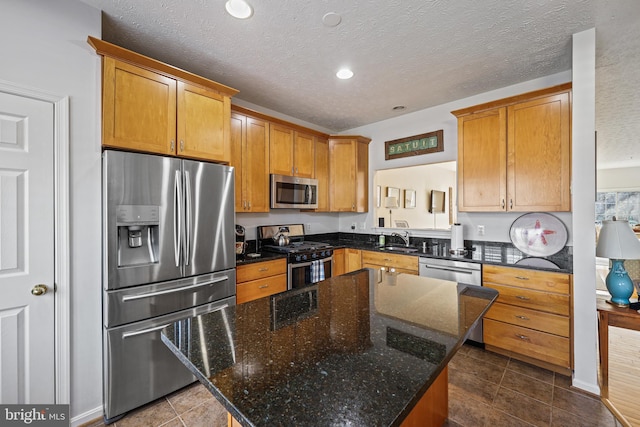 kitchen with stainless steel appliances, a center island, sink, and dark stone counters