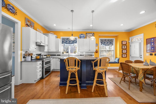 kitchen with white cabinetry, stainless steel appliances, decorative light fixtures, and a kitchen island