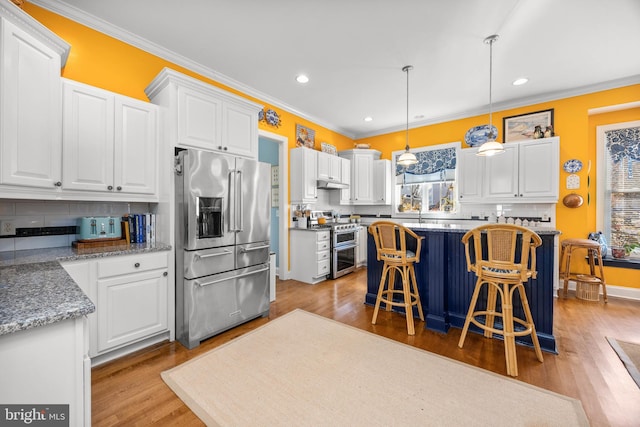 kitchen with white cabinetry, a center island, hanging light fixtures, a wealth of natural light, and stainless steel appliances