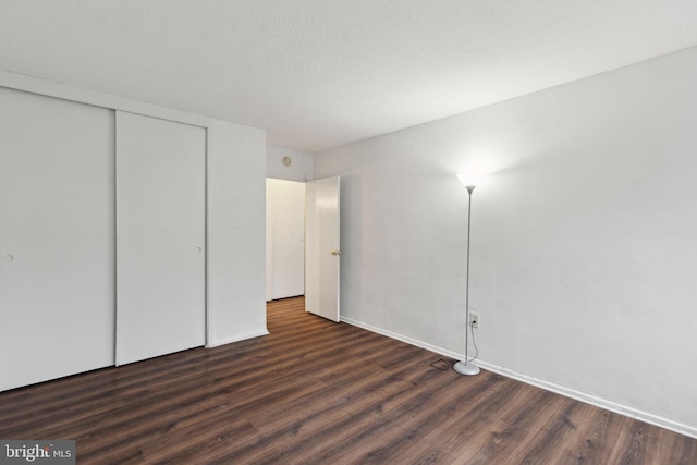 unfurnished bedroom with dark wood-type flooring, a closet, and a textured ceiling