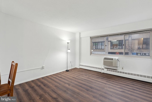 spare room featuring a wall mounted air conditioner, dark hardwood / wood-style floors, and a baseboard heating unit