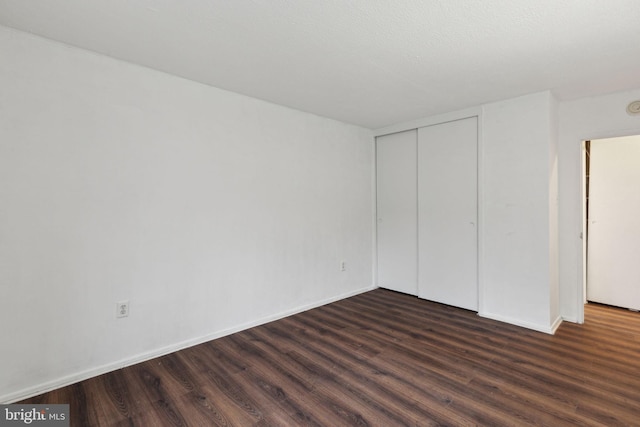 unfurnished bedroom featuring dark hardwood / wood-style flooring and a closet