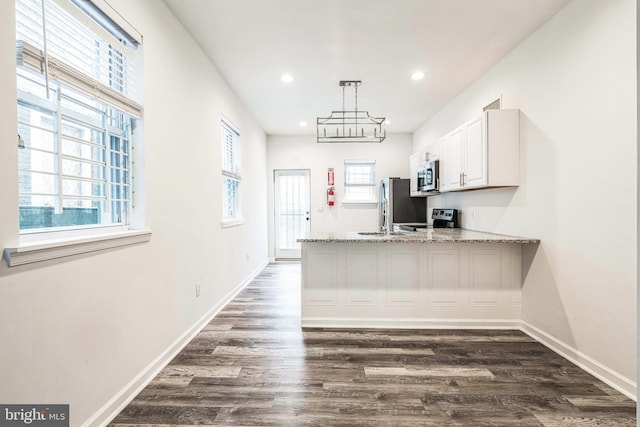 kitchen with baseboards, dark wood-type flooring, a peninsula, stainless steel appliances, and white cabinetry