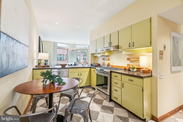 kitchen featuring a sink, yellow cabinetry, dark countertops, and appliances with stainless steel finishes