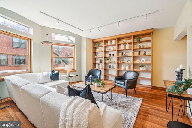 living area featuring baseboards, hardwood / wood-style floors, and track lighting