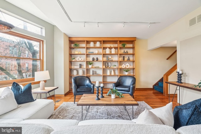 living room with visible vents, stairway, and wood finished floors