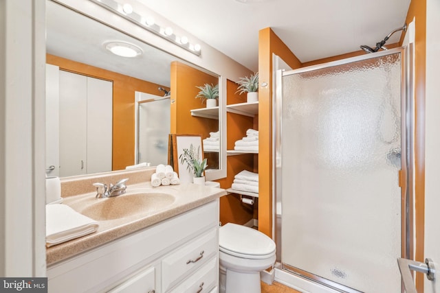 bathroom featuring toilet, a stall shower, and vanity