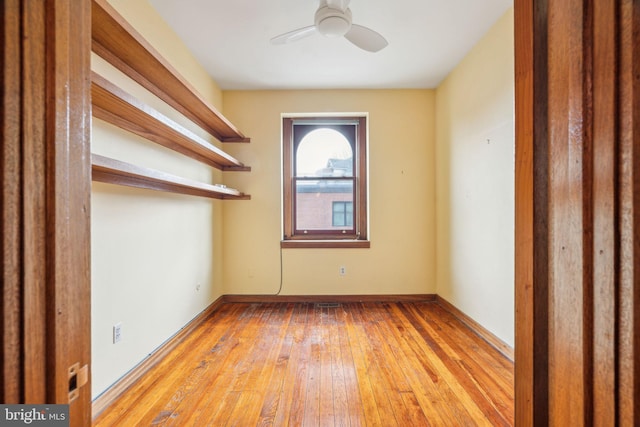 unfurnished room with hardwood / wood-style floors, a ceiling fan, and baseboards