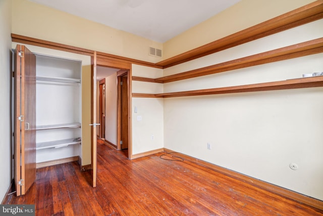 unfurnished bedroom with visible vents, baseboards, a closet, and hardwood / wood-style floors