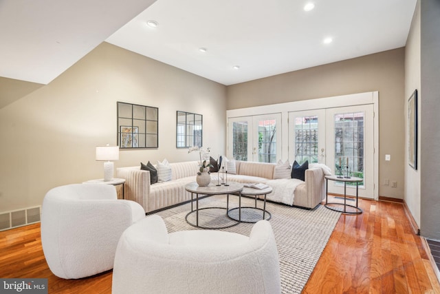 living room featuring visible vents, baseboards, wood finished floors, and french doors