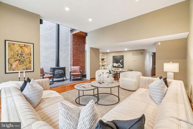 living area featuring visible vents, expansive windows, wood finished floors, recessed lighting, and a wood stove