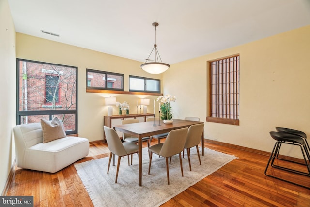 dining space with visible vents, baseboards, and hardwood / wood-style flooring