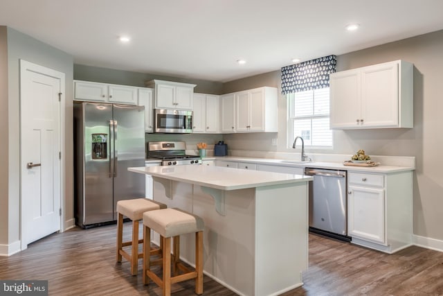 kitchen with sink, white cabinetry, appliances with stainless steel finishes, a kitchen breakfast bar, and a kitchen island