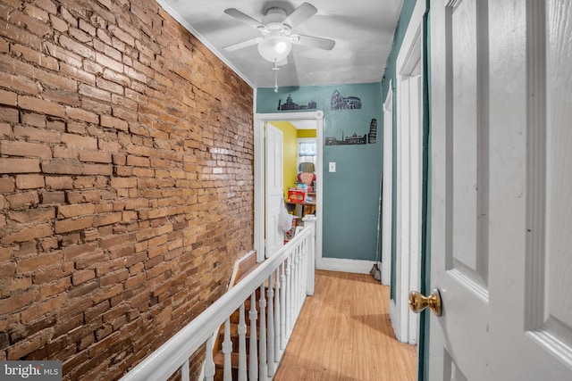 corridor featuring light wood-type flooring and brick wall