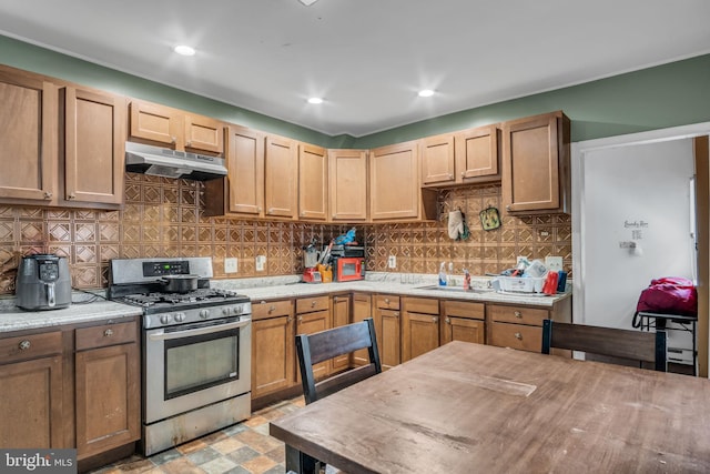 kitchen with light stone counters, sink, decorative backsplash, and gas stove