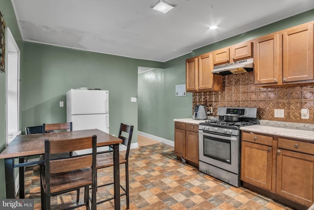 kitchen with decorative backsplash, gas stove, and white fridge