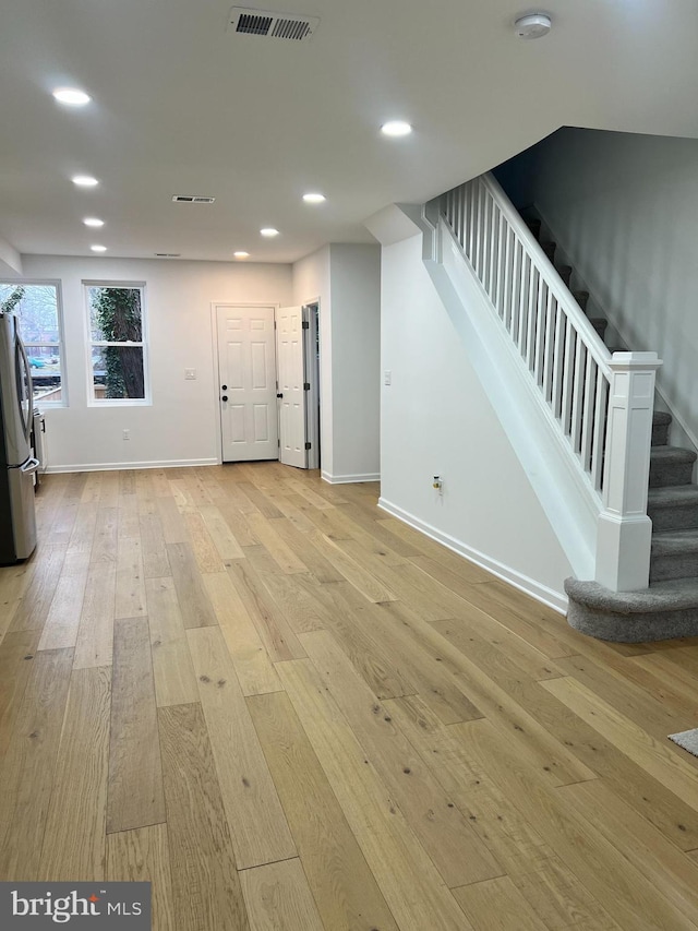 basement featuring stainless steel fridge and light hardwood / wood-style floors