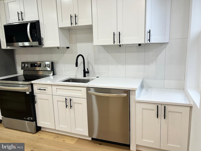 kitchen featuring tasteful backsplash, appliances with stainless steel finishes, sink, and white cabinets
