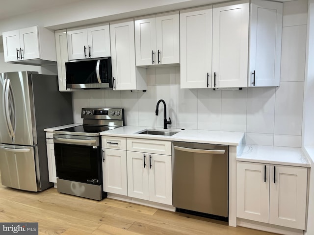 kitchen featuring stainless steel appliances, tasteful backsplash, sink, and white cabinets