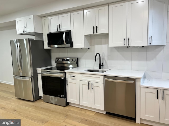 kitchen featuring white cabinetry, appliances with stainless steel finishes, sink, and decorative backsplash
