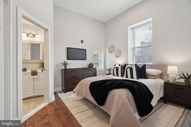 bedroom featuring multiple windows, connected bathroom, and light hardwood / wood-style floors